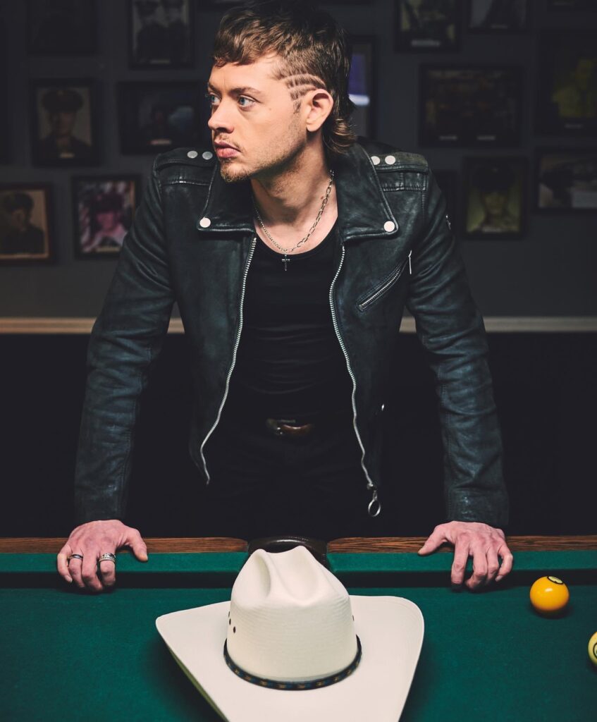 man leaning on pool table with cowboy hat off