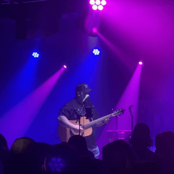 Man playing guitar on stage under lights